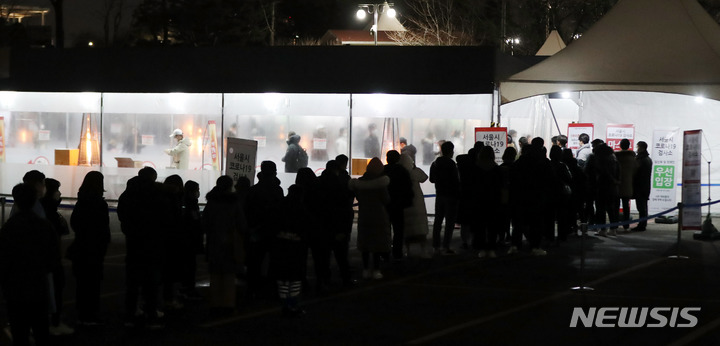 [서울=뉴시스] 추상철 기자 = 코로나19의 신규 확진자가 급속한 확산세를 보인 24일 오후 서울 송파구 잠실종합운동장 제2주차장 임시선별검사소에서 밤 늦은 시간에도 코로나19 검사를 받으려는 시민들이 길게 줄지어 서 있다. 2022.01.24. scchoo@newsis.com