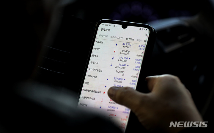 [서울=뉴시스] 서울 도심에서 한 개인투자자가 스마트폰을 통해 하락하고 있는 주식종목을 살펴보고 있다. (사진=뉴시스 DB). photo@newsis.com