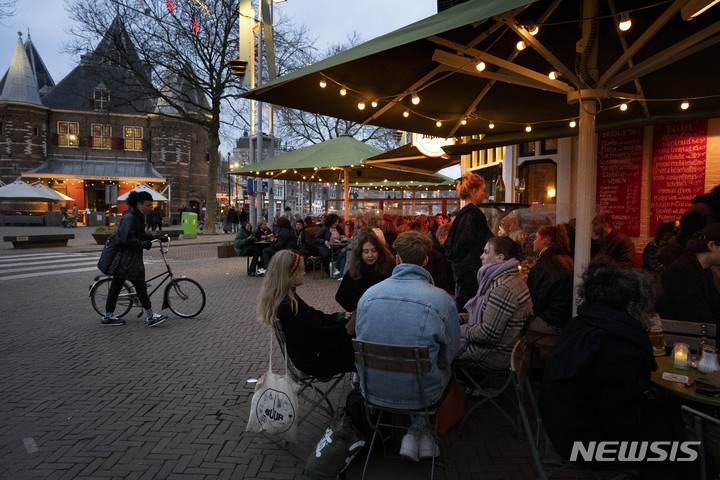 [암스테르담=AP/뉴시스] 26일(현지시간) 네덜란드 암스테르담의 식당 야외 테이블에 손님들이 앉아 있다. 마르크 뤼터 네덜란드 총리가 코로나19 급증에도 봉쇄 장기화에 따른 여론 반발에 지난 25일 방역 지침 완화를 발표해 올해 처음으로 식당, 술집, 박물관 등의 영업이 재개됐다. 2022.01.27.