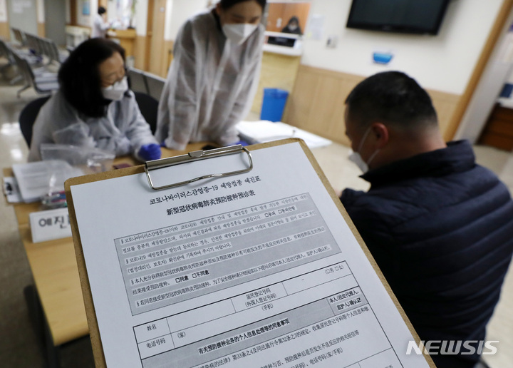 [서울=뉴시스] 이영환 기자 = 지난달 27일 오전 서울 영등포구보건소분소에서 한 외국인이 코로나19 백신 접종을 위해 예진표를 작성하고 있다. 2022.01.27. 20hwan@newsis.com