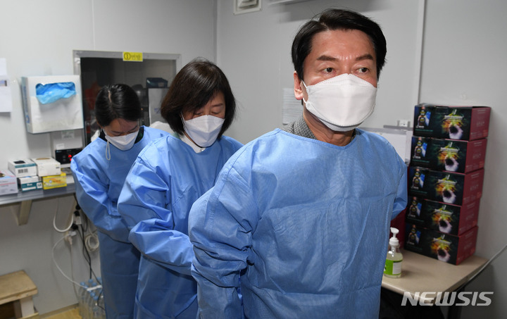 [서울=뉴시스] 최진석 기자 = 안철수 국민의당 대선후보가 설 연휴 마지막 날인 2일 서울 중구보건소 선별진료소를 찾아 부인 김미경 교수, 딸 안설희 박사와 함께 코로나19 검체 채취 봉사활동을 하기 앞서 가운을 착용하고 있다. 딸 안설희 박사는 행정 업무 등을 지원했다. (공동취재사진) 2022.02.02. photo@newsis.com