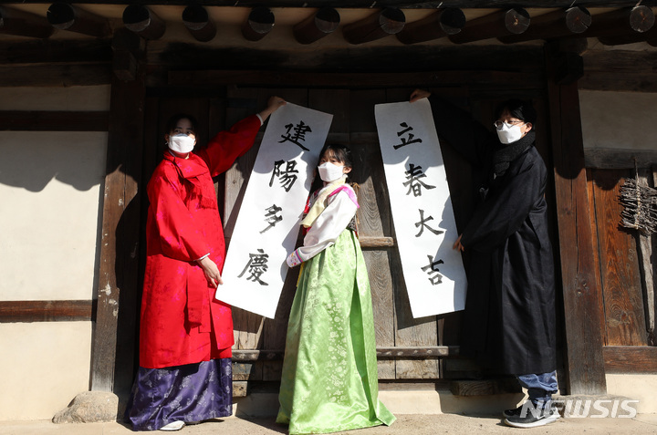 [서울=뉴시스] 이영환 기자 = 절기상 입춘(立春)을 하루 앞둔 지난해 2월3일 오전 서울 종로구 국립민속박물관 오촌댁에서 박진우 서예가 등이 입춘첩을 대문에 붙이고 있다. 2022.02.03. 20hwan@newsis.com