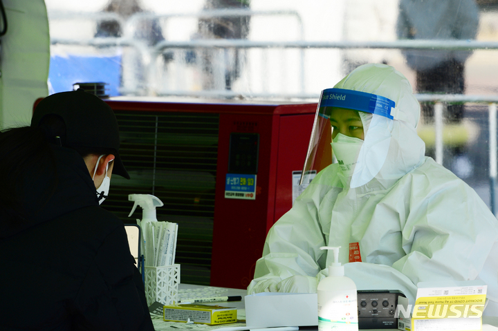 [창원=뉴시스] 차용현 기자 = 6일 오전 경남 창원시 성산구 창원스포츠파크에 차려진 선별진료소에서 한 의료진이 신속항원검사를 하고 있는 시민을 지켜보고 있다. 2022.02.06. con@newsis.com