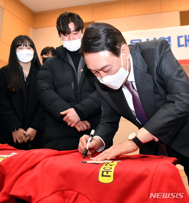 [광주=뉴시스] 류형근 기자 = 윤석열 국민의힘 대선후보가 지난 달 6일 오후 광주 서구 김대중컨벤션센터에서 열린 지역기자간담회에서 청년들로부터 받은 옷에 사인을 하고 있다. 2022.02.06. hgryu77@newsis.com
