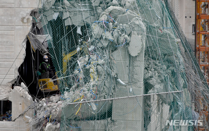 [광주=뉴시스] 변재훈 기자 = 7일 오전 광주 서구 HDC현대산업개발 아파트 신축 공사 붕괴 사고 현장에서 소형 굴착기가 상층부 낙하 방지망 인근에서 잔해물 제거 작업을 벌이고 있다. 사고 28일째인 이날까지 매몰자 1명과 실종자 1명에 대한 구조·수색 작업이 펼쳐지고 있다. 2022.02.07. wisdom21@newsis.com