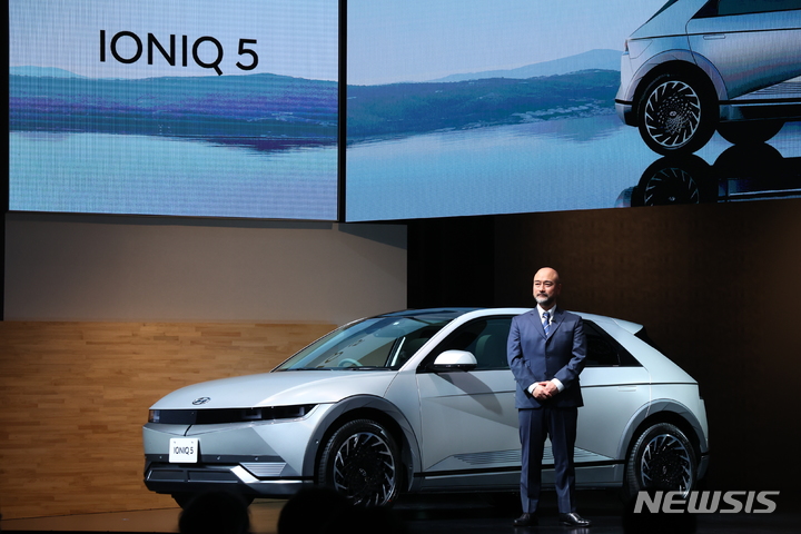 [서울=뉴시스] 8일 일본 도쿄 오테마치 미쓰이홀에서 열린 현대차 미디어 간담회에서 우라베 타카오 HMJ 연구개발(R&D)센터 디자인팀장이 아이오닉 5 앞에서 발표하고 있다. (사진=현대차그룹 제공)