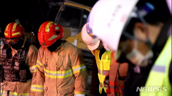 [양주=뉴시스] 경기 양주시 삼표산업 채석장 토사 붕괴 매몰사고로 마지막 작업자가 발견되자 소방대원과 관계자들이 일제히 고개를 숙이고 묵념하고 있다. (사진=경기북부소방재난본부 제공)