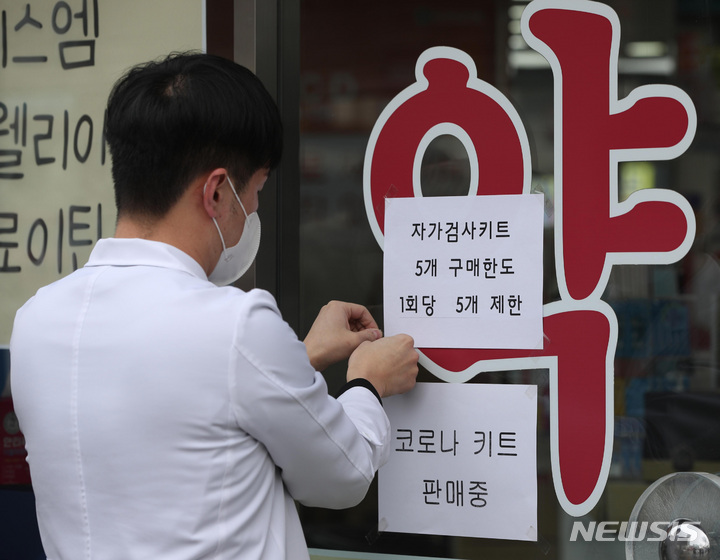 [서울=뉴시스] 이영환 기자 = 지난 13일 오전 서울 종로구 유성약국에서 한 약사가 자가검사키트 판매 안내문을 게시하고 있다. 자가검사키트는 유통개선조치에 따라 이날부터 3월 5일까지 온라인판매가 금지되고 개인이 약국·편의점에서 구매할 수 있는 물량은 한 번에 5개로 제한된다. 다만 하루에 여러번 구매하는 것에는 제한이 없으며 온라인 재고 물량은 16일까지 판매할 수 있다. (공동취재사진) 2022.02.13. photo@newsis.com