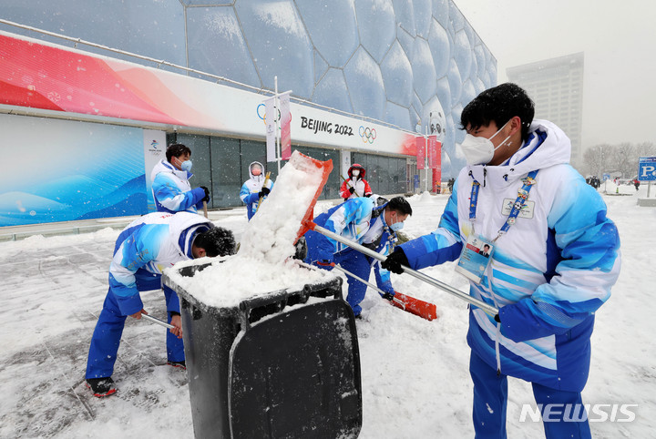 [베이징(중국)=뉴시스] 고범준 기자 = 2022 베이징 동계올림픽이 진행중인 13일 중국 베이징 내셔널 아쿠아틱 센터에서 자원봉사자 등 관계자들이 내리는 눈을 치우고 있다. 2022.02.13. bjko@newsis.com