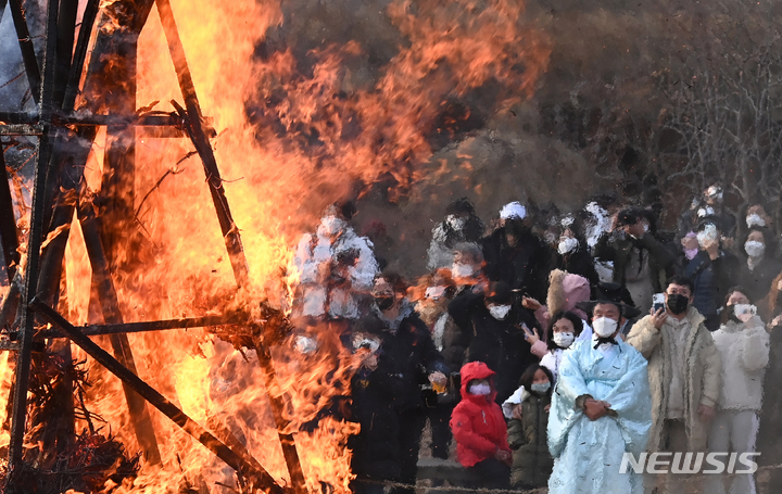 [용인=뉴시스] 김종택기자 = 13일 오후 경기도 용인 한국민속촌에서 열린 정월대보름 달집태우기 행사에서 관람객들이 활활 타오르는 달집을 바라보고 있다. 2022.02.13. jtk@newsis.com