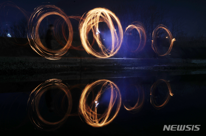 [전주=뉴시스] 김얼 기자 = 음력 새해의 첫 보름날을 뜻하는 정월대보름을 하루 앞둔 14일 전북 전주시 전주천 상류에서 시민들이 쥐불놀이를 하며 즐거운 시간을 보내고 있다. 쥐불놀이는 정월대보름 기간에 하는 전통 민속놀이로서 논둑과 밭둑에 불을 놓아 전염병을 옮기는 들쥐나 해충을 제거하여 한 해 농사 시작에 도움이 될 수 있게 하는 풍습이다. (전북사진기자단 공동취재 사진) 2022.02.14. pmkeul@nwsis.com