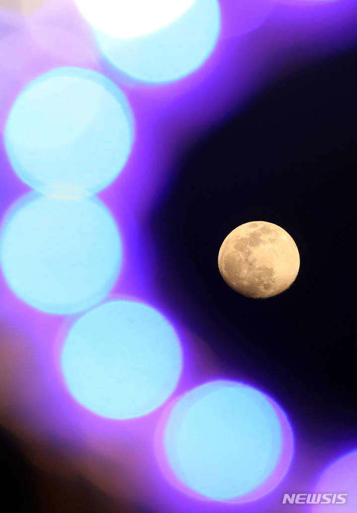 [부산=뉴시스] 하경민 기자 = 정월대보름을 하루 앞둔 14일 오후 부산 수영구의 한 가로등 사이로 둥근 달이 환하게 떠오르고 있다. 2022.02.14. yulnetphoto@newsis.com