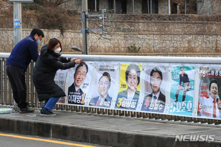 [제주=뉴시스] 우장호 기자 = 18일 오전 제주시 이도1동 동문시장 인근 거리에 제주시선관위 직원 등 관계자들이 제20대 대통령선거 선거벽보를 부착하고 있다. 2022.02.18. woo1223@newsis.com