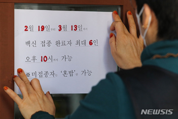 [서울=뉴시스] 권창회 기자 = 정부가 사회적 거리두기 방침을 일부 완화한 지난 18일 오후 서울 시내 한 식당에서 관계자가 새로운 거리두기 안내문을 붙이고 있다. 오는 19일부터 다음달 13일까지 개편되는 방역체계에 따라 '사적모임 6인, 오후 10시'로 완화된다. 2022.02.18. kch0523@newsis.com