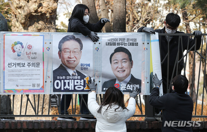 [서울=뉴시스] 권창회 기자 = 종로구 선거관리위원회 직원들이 18일 오후 서울 종로구 이화동 예술가의 집 울타리에서 제20대 대통령 선거 후보자들의 선거 벽보를 첩부하고 있다. 2022.02.18. kch0523@newsis.com