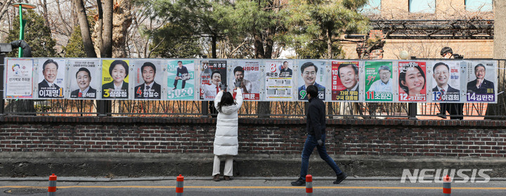 [서울=뉴시스] 권창회 기자 = 종로구 선거관리위원회 직원들이 18일 오후 서울 종로구 이화동 예술가의 집 울타리에서 제20대 대통령 선거 후보자들의 선거 벽보를 첩부하고 있다. 2022.02.18. kch0523@newsis.com