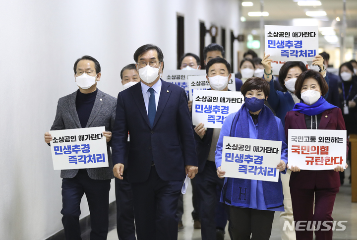 [서울=뉴시스] 최진석 기자 = 더불어민주당 맹성규 예결위 간사를 비롯한 여당 의원들이 18일 서울 여의도 국회 이종배 예산결산특별위원회 위원장실로 추경안 처리 촉구 피켓을 들고 예결위 회의 속개를 촉구하기 위해 향하고 있다. 2022.02.18. myjs@newsis.com