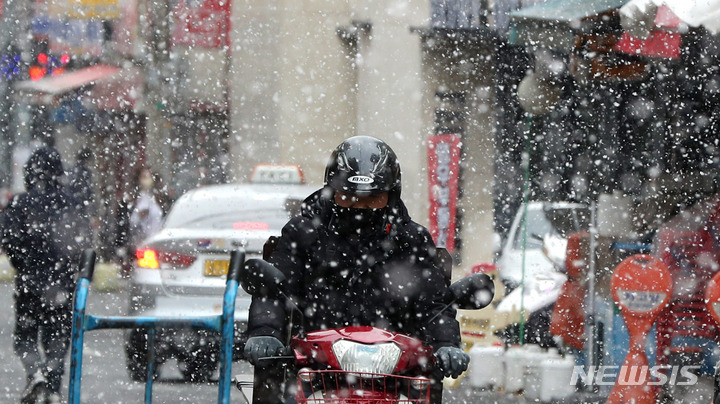 [서울=뉴시스] 추상철 기자 = 눈이 내린 지난달 21일 오후 서울 도심에서 라이더가 배달을 하고 있다. 2022.02.21. scchoo@newsis.com