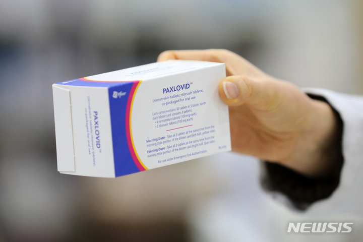 [서울=뉴시스] 백동현 기자 =지난달 21일 오후 서울 시내 한 약국에서 약사가 경구용 코로나19 치료제 팍스로비드를 들어 보이고 있다. 2022.03.11. livertrent@newsis.com