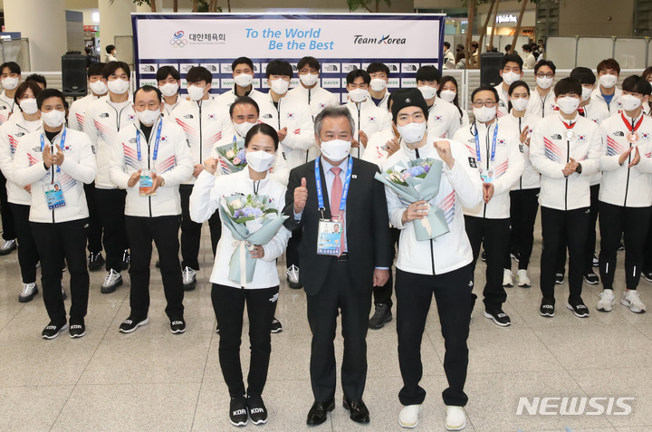 [인천공항=뉴시스] 조수정 기자 = 2022 베이징 동계올림픽에 출전했던 대한민국 선수단 대표 컬링 김은정, 스피드 스케이팅 차민규가 21일 오후 인천국제공항 제2터미널을 통해 귀국, 입국장에서 열린 환영행사에서 이기흥 대한체육회장으로부터 꽃다발을 받은 뒤 기념촬영 하고 있다. 2022.02.21. chocrystal@newsis.com