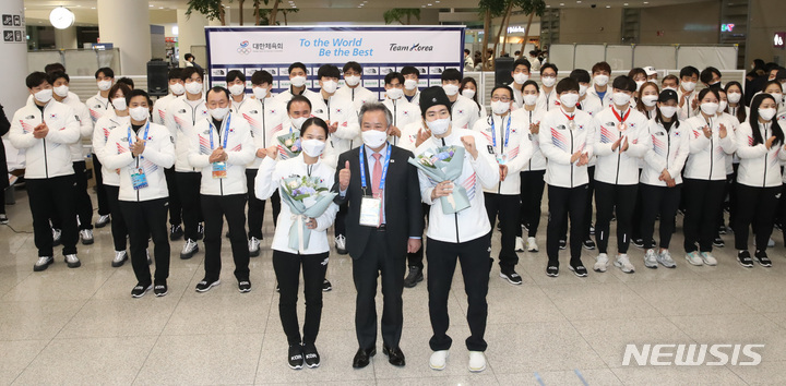 [인천공항=뉴시스] 조수정 기자 = 2022 베이징 동계올림픽에 출전했던 대한민국 선수단 대표 컬링 김은정, 스피드 스케이팅 차민규가 21일 오후 인천국제공항 제2터미널을 통해 귀국, 입국장에서 열린 환영행사에서 이기흥 대한체육회장으로부터 꽃다발을 받은 뒤 기념촬영 하고 있다. 2022.02.21. chocrystal@newsis.com