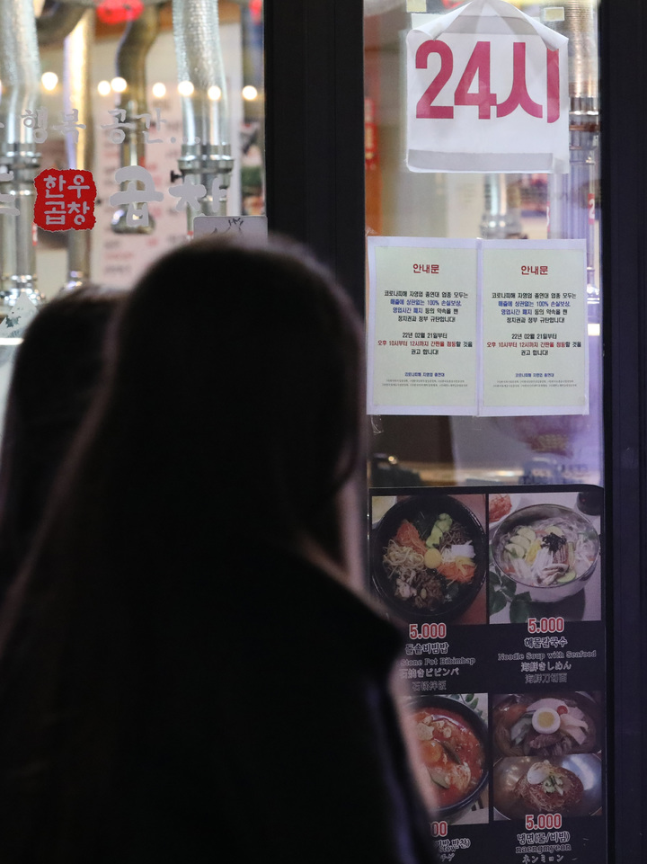 [서울=뉴시스] 조수정 기자 = 한국외식업중앙회와 한국유흥음식업중앙회 등 14개 소상공인 단체로 구성된 코로나피해자영업총연합(코자총) 소속 서울 홍대입구역 인근 음식점 상인들이 21일 코로나19 영업 제한시간인 오후 10시 이후 영업점 불을 켜고 점등 시위를 하고 있다. 유리창에는 간판 점등을 권고하는 안내문이 붙어 있다. 코자총은 영업시간 제한 폐지와 자영업자 실질적인 손실보상 100% 지급 등의 약속을 깬 정치권과 정부를 규탄하며 간판 및 영업점 점등시위를 시작했다. 2022.02.21. chocrystal@newsis.com