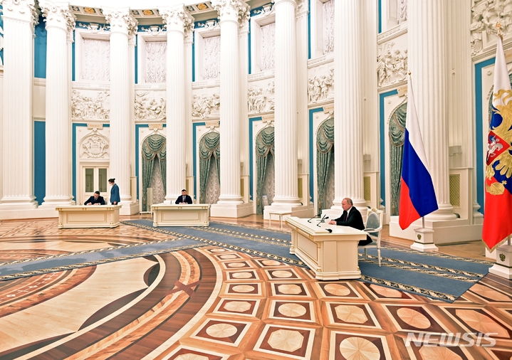 [모스크바=AP/뉴시스] 블라디미르 푸틴 러시아 대통령이 21일(현지시간) 모스크바 크렘린궁에서 우크라이나 동부 분쟁 지역인 돈바스 지역(도네츠크, 루한스크)의 독립을 인정하는 문서에 서명하고 있다. 이명령에 따라 러시아군이 우크라이나에 처음 진입한 23일은 러시아 조국 수호 의 날이었다. 2022.02.22.