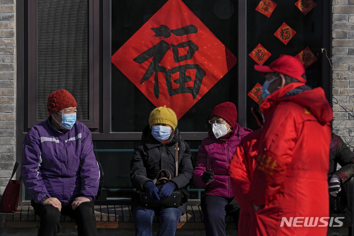 [베이징(중국)=AP/뉴시스]지난 22일 중국 베이징에서 시민들이 마스크를 착용한 채 앉아있다. 2022.02.23.