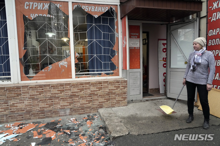 [키예프=AP/뉴시스] 24일(현지시간) 우크라이나 수도 키예프에서 한 주민이 러시아의 포격으로 산산이 조각난 창문의 유리 조각을 치우고 있다. 2022.02.24.