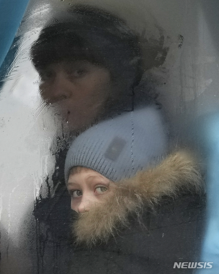 [루간스크=AP/뉴시스]24일(현지시간) 우크라이나 동부 루간스크 지역을 떠나는 버스에 탑승한 여성과 어린이가 창밖을 바라보고 있다. 2022.2.24.