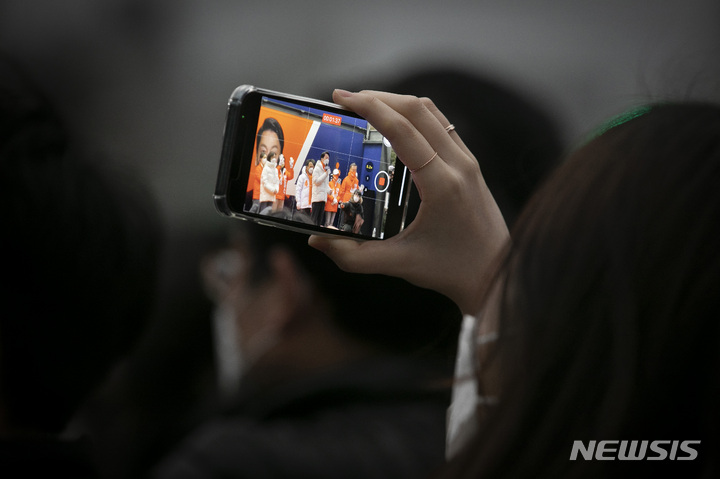 [서울=뉴시스] 국회사진기자단 = 26일 서울 종로구 광장시장 인근에서 한 시민이 안철수 국민의당 대선 후보의 유세를 촬영하고 있다. 2022.02.26. photo@newsis.com