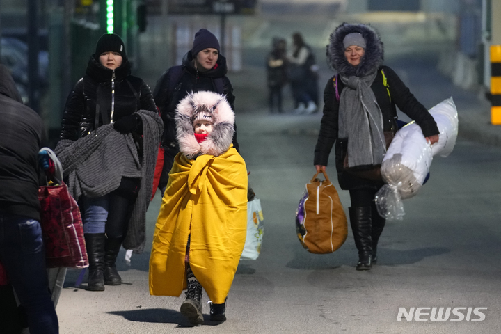 [프르제미슬(폴란드)=AP/뉴시스]러시아의 침공을 피해 탈출한 우크라이나 국민들이 27일 폴란드 프르제미슬에서 국경을 넘고 있다. 유럽연합(EU) 내무부 장관들이 27일 러시아의 우크라이나 침공으로 국경을 넘어 폴란드, 헝가리, 루마니아 등지로 피난하는 우크라이나 난민들의 유입에 대처하기 위한 긴급 회담을 소집했다. 2022.2.27