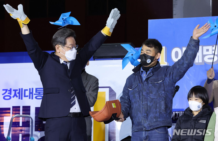 [울산=뉴시스] 최동준 기자 = 이재명 더불어민주당 대선 후보가 27일 울산 남구 롯데백화점 앞에서 열린 유세에서 용접공 장갑을 선물 받고 손을 들어올리고 있다. 2022.02.27. photocdj@newsis.com