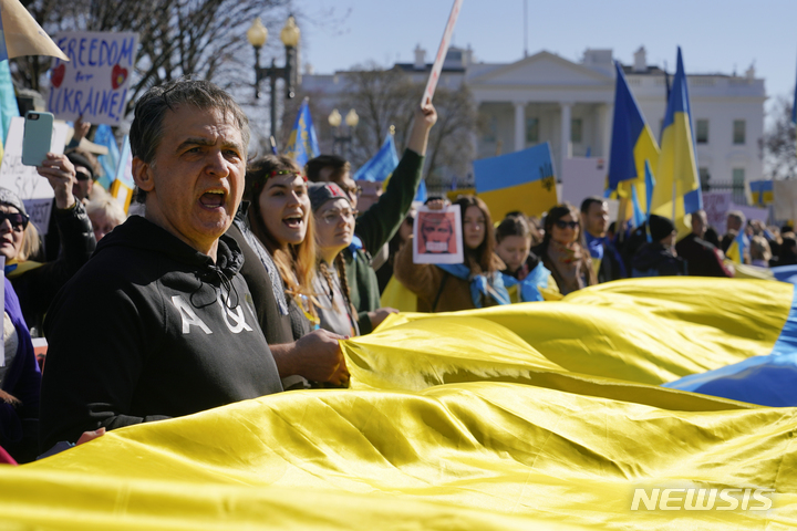 [워싱턴=AP/뉴시스] 27일(현지시간) 워싱턴 백악관 밖에서 러시아의 우크라이나 침공에 반대하는 시위가 열려 시위대가 대형 우크라이나 국기를 들고 있다. 2022.02.28.