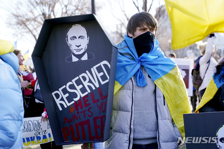 [워싱턴=AP/뉴시스] 27일(현지시간) 워싱턴 백악관 밖에서 러시아의 우크라이나 침공에 반대하는 시위에 참여한 한 남성이 블라디미르 푸틴 러시아 대통령의 사진이 담긴 관을 들고 있다. 2022.02.28.