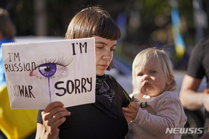 [샌타모니카=AP/뉴시스] 지난달 27일(현지시간) 미 캘리포니아주 샌타모니카에서 러시아 태생인 카트리나 레피나가 딸 조이를 안고 "나는 러시아인이지만 전쟁엔 반대한다" "우크라이나에 미안"이라고 쓰인 손팻말을 들고 있다. 레피나는 푸틴을 지지하지 않는다고 밝히면서 " 우크라이나 국민의 고통을 대신하고 싶다"라고 말했다. 그는 인스타그램을 통해 친해진 우크라이나 친구 한나 후사코바와 함께 우크라이나 지지 시위에 나섰다. 2022.03.01.