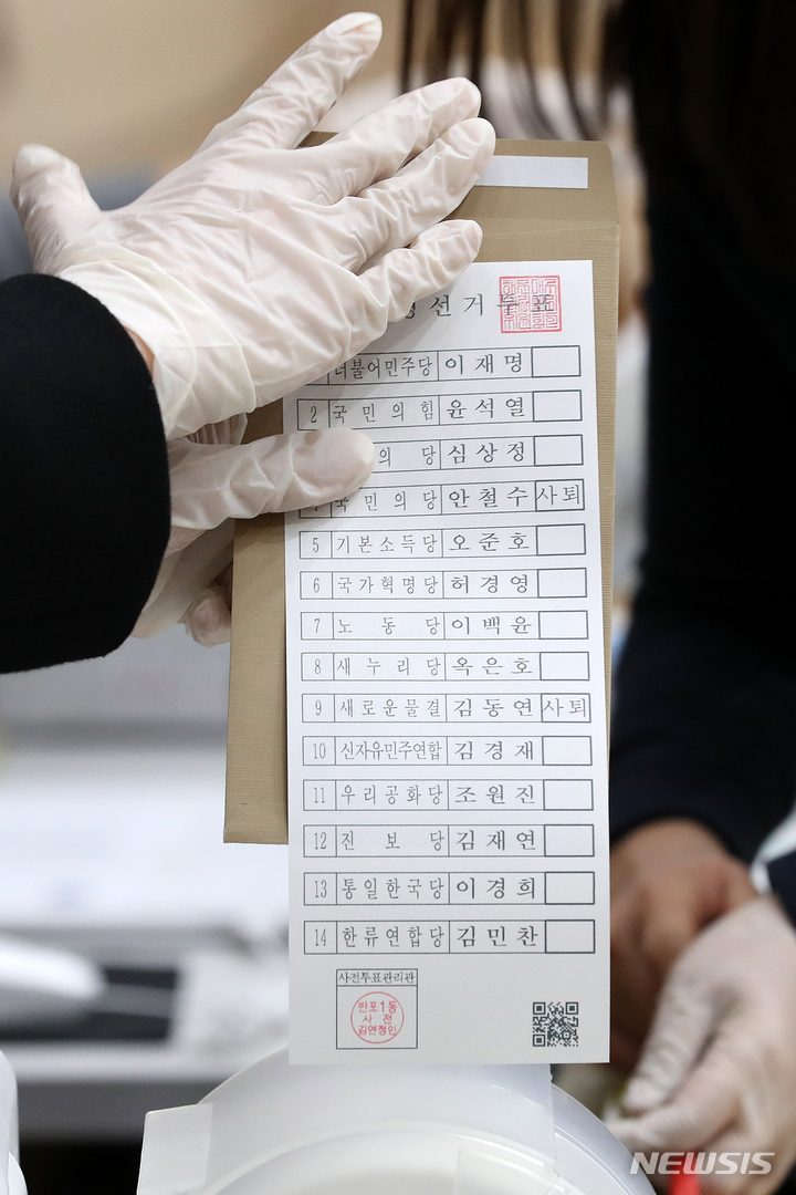 [서울=뉴시스] 백동현 기자 = 제20대 대통령선거 사전투표가 시작된 4일 오전 서울 서초구 반포1동 주민센터에 마련된 사전투표소에서 관계자가 안철수 국민의당 대표와 김동연 전 경제부총리 투표란에 '사퇴' 표시된 투표지를 전달하고 있다. 2022.03.04. livertrent@newsis.com