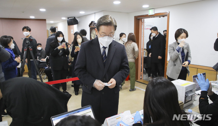 [서울=뉴시스] 국회사진기자단 = 이재명 더불어민주당 대선 후보가 4일 오전 서울 중구 소공동 주민센터에 설치된 사전투표소에서 사전투표를 하기 위해 본인 확인을 하고 있다. 2022.03.04. photo@newsis.cmo