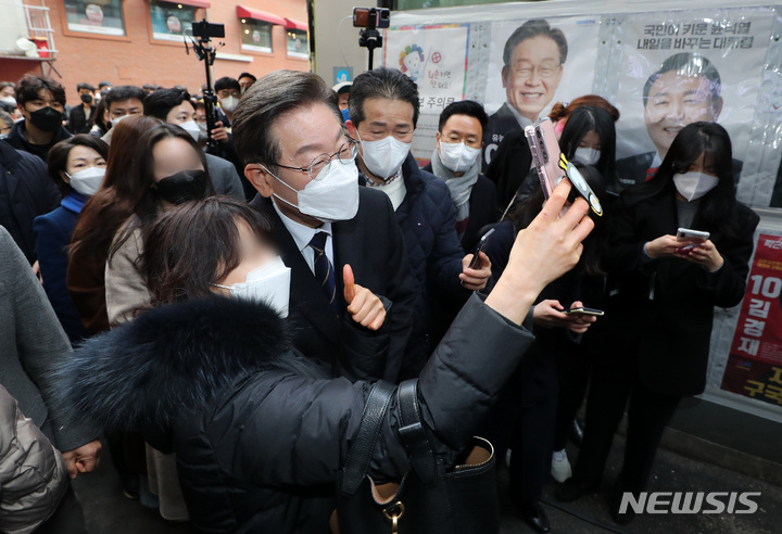 [서울=뉴시스] 국회사진기자단 = 이재명 더불어민주당 대선후보가 4일 오전 서울 중구 소공동 주민센터에 마련된 사전투표소에서 투표에 앞서 시민들과 셀카를 찍고 있다. 2022.03.04. photo@newsis.com
