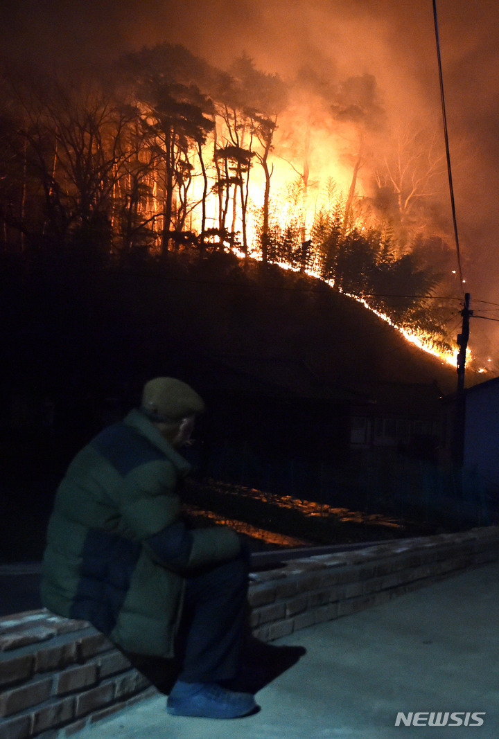 [울진=뉴시스] 이무열 기자 = 4일 경북 울진군 북면 두천리에서 일어난 산불이 강풍을 타고 마을까지 번지자 급히 대피한 주민이 거센 불길을 바라보고 있다. 2022.03.04. lmy@newsis.com