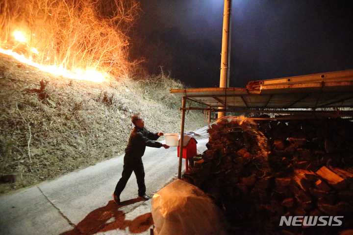 [강릉=뉴시스] 김경목 기자 = 5일 새벽 강원도 강릉시 옥계면 남양리 백봉령 일대 매봉산에서 발생한 산불로 인해 주택 화재가 발생하는 가운데 주민이 장작에 물을 붓고 있다. 2022.03.05. photo31@newsis.com
