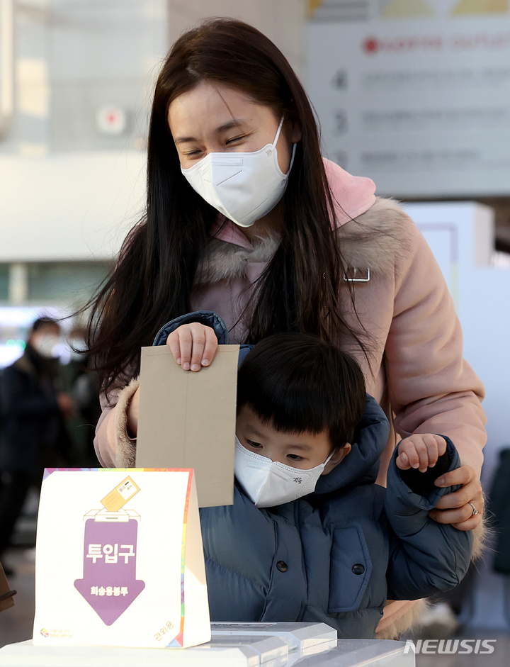 [서울=뉴시스] 김병문 기자 = 제20대 대통령선거 사전투표 이틀째인 지난 5일 오후 서울역 설치된 남영동 사전투표소에서 한 어린이가 어머니의 투표용지를 투표함에 넣고 있다. 2022.03.07. dadazon@newsis.com