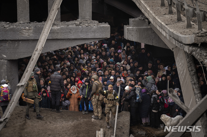 [이르핀=AP/뉴시스] 5일(현지시간) 우크라이나 이르핀 마을의 강을 건너려는 피난길 주민들이 러시아군의 공습으로 파괴된 다리 밑에 모여 있다. 이들은 파괴된 다리 밑에 급조된 좁은 통로를 통해 강을 건넜다. 2022.03.06.