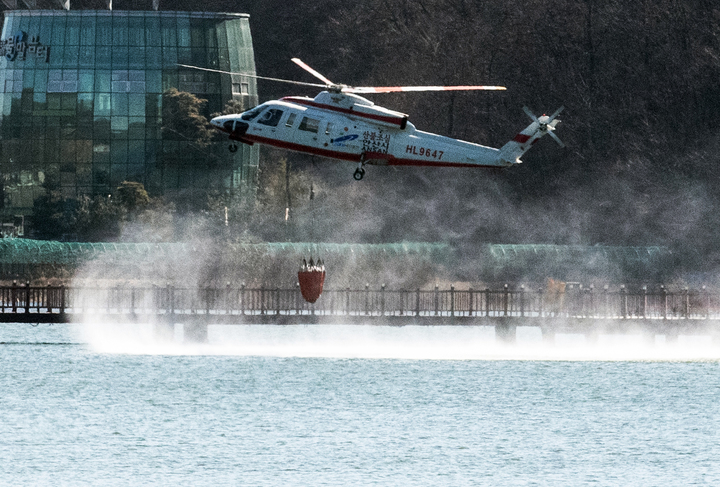 [안산=뉴시스] 김종택기자 = 산불 진화 헬기가 6일 오전 경기도 안산시 수리산 일대에서 발생한 산불을 진화하기 위해 인근 저수지에서 담수하고 있다. (사진= 중부일보 제공) 2022.03.06. photo@newsis.com *재판매 및 DB 금지