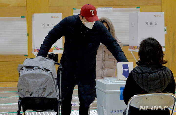 [광주=뉴시스] 변재훈 기자 = 제20대 대통령 선거 투표일인 9일 오전 광주 광산구 첨단다목적체육센터(첨단2동 제10투표소)에서 한 유권자가 유모차를 끌며 기표 용지를 투표함에 넣고 있다. 2022.03.09. wisdom21@newsis.com