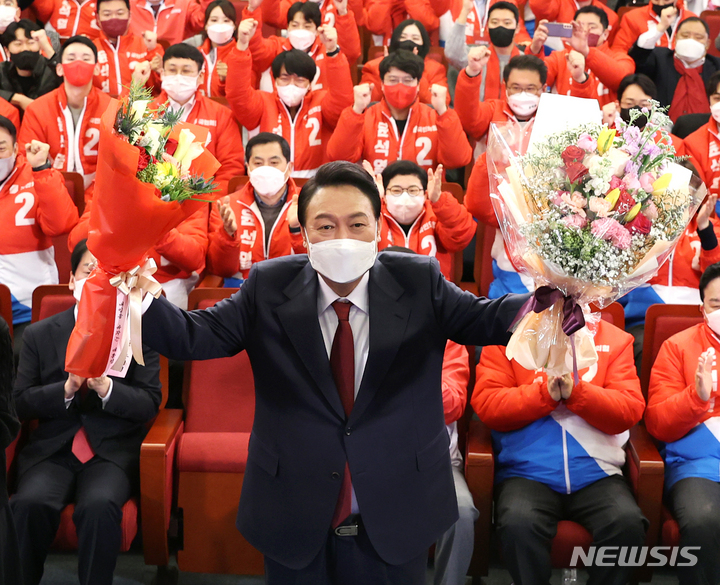 [서울=뉴시스] 전신 기자 = 윤석열 제20대 대통령 당선인이 10일 새벽 서울 여의도 국회도서관에 마련된 국민의힘 제20대 대통령선거 개표상황실에서 꽃다발을 들고 있다. (공동취재사진) 2022.03.10. photo@newsis.com