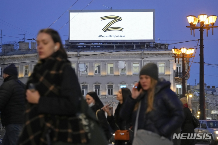 [상트페테르부르크=AP/뉴시스] 3월 9일 러시아 상트페레르부르크에서 시민들이 우크라이나 침공 지지 상징인 'Z 표식'이 노출된 전광판 아래 거리를 지나가고 있다. 표식 아래 문구는 "우리는 우리의 것을 버리지 않는다"라는 뜻이다.