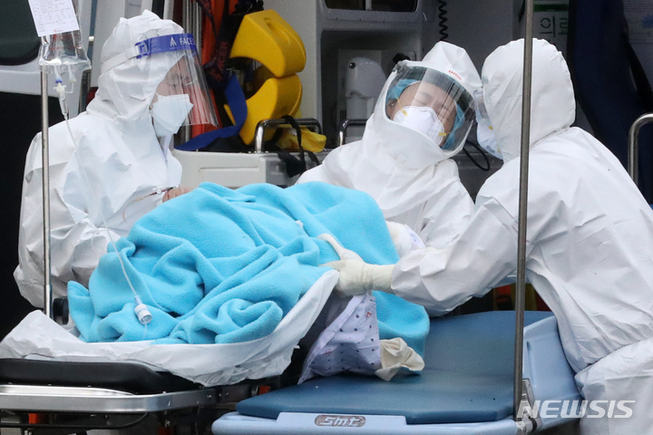 [서울=뉴시스] 백동현 기자 = 코로나19 위중증 환자가 1116명으로 나흘 연속 네 자릿수를 나타내고 있는 11일 오후 서울 중랑구 서울의료원에서 의료진들이 확진 환자를 이동 침대로 옮기고 있다. 2022.03.11. livertrent@newsis.com