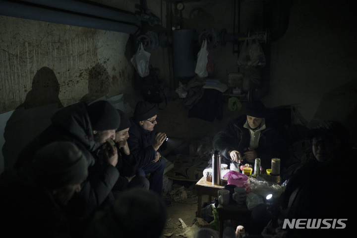 [이르핀=AP/뉴시스] 13일(현지시간) 우크라이나 키이우 외곽 이르핀에서&nbsp; 방공호로 쓰이는 지하실에 대피한 주민들이 손전등을 밝혀 따뜻한 차를 준비하고 있다. 2022.03.14.