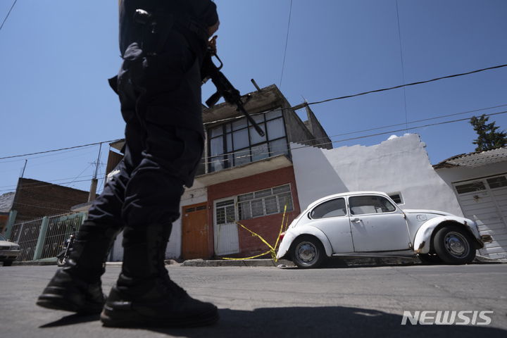 [지타쿠아로( 멕시코)= AP/뉴시스] 멕시코에서 올해 3월 16일 총격으로 피살된 아르만도 리나레스 기자의 집 앞에서 무장경찰관이 경비를 하고 있다.  8월22일 살해된 프레디드 로만 기자는 한 달 전에 아들까지 살해된 사실이 뒤늦게 밝혀졌다.  